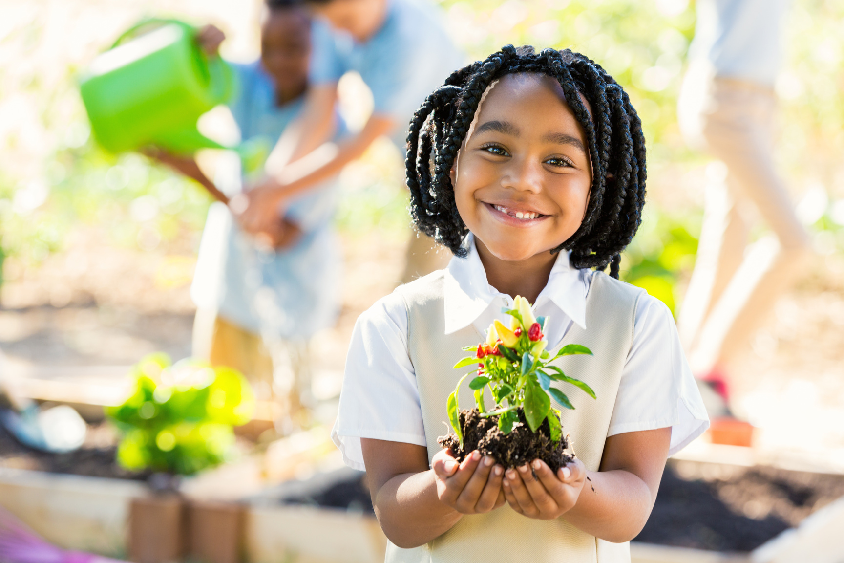 African American student holding plant while gardening during science class